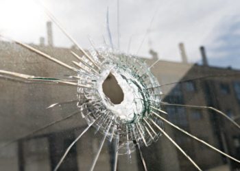 Broken glass with hole and building reflected in the window